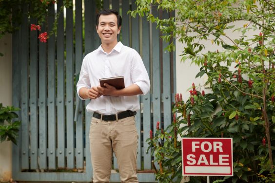 Smiling Real Estate Agent with Tablet Computer Portrait of smiling real estate agent with tablet computer standing at gate of house on sale